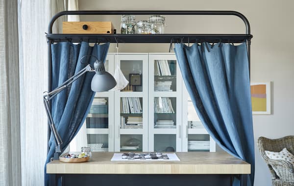 Una illa de cuina ubicada en una sala. El marc superior fa d’espai d’emmagatzematge i està decorat amb cortines blaves.