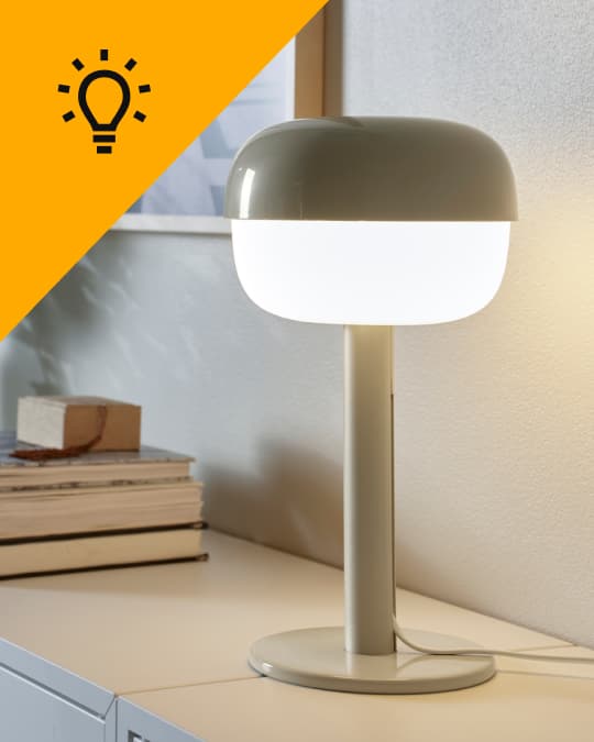 Una lámpara de mesa IKEA encendida sobre un muebles.