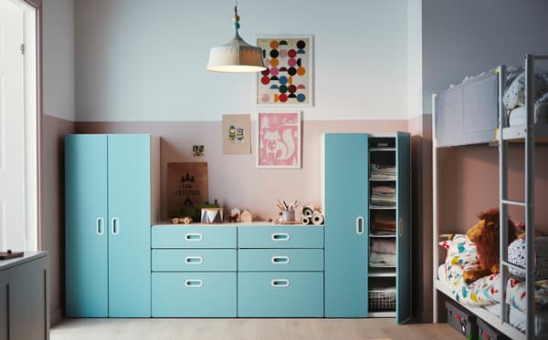 Una lámpara de techo verde con diseño de carpa de circo en una habitación infantil de IKEA con un armario en azul turquesa y una litera.