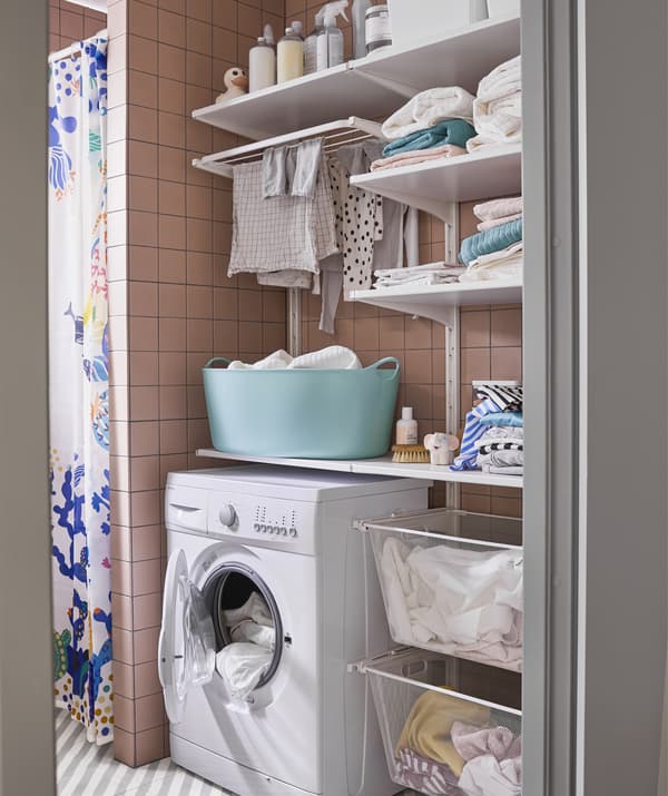 Una lavanderia con una lavatrice, mensole e cesti.