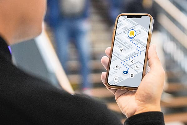 Una mà sosté un telèfon que mostra l'aplicació IKEA i la funció de navegació a la botiga