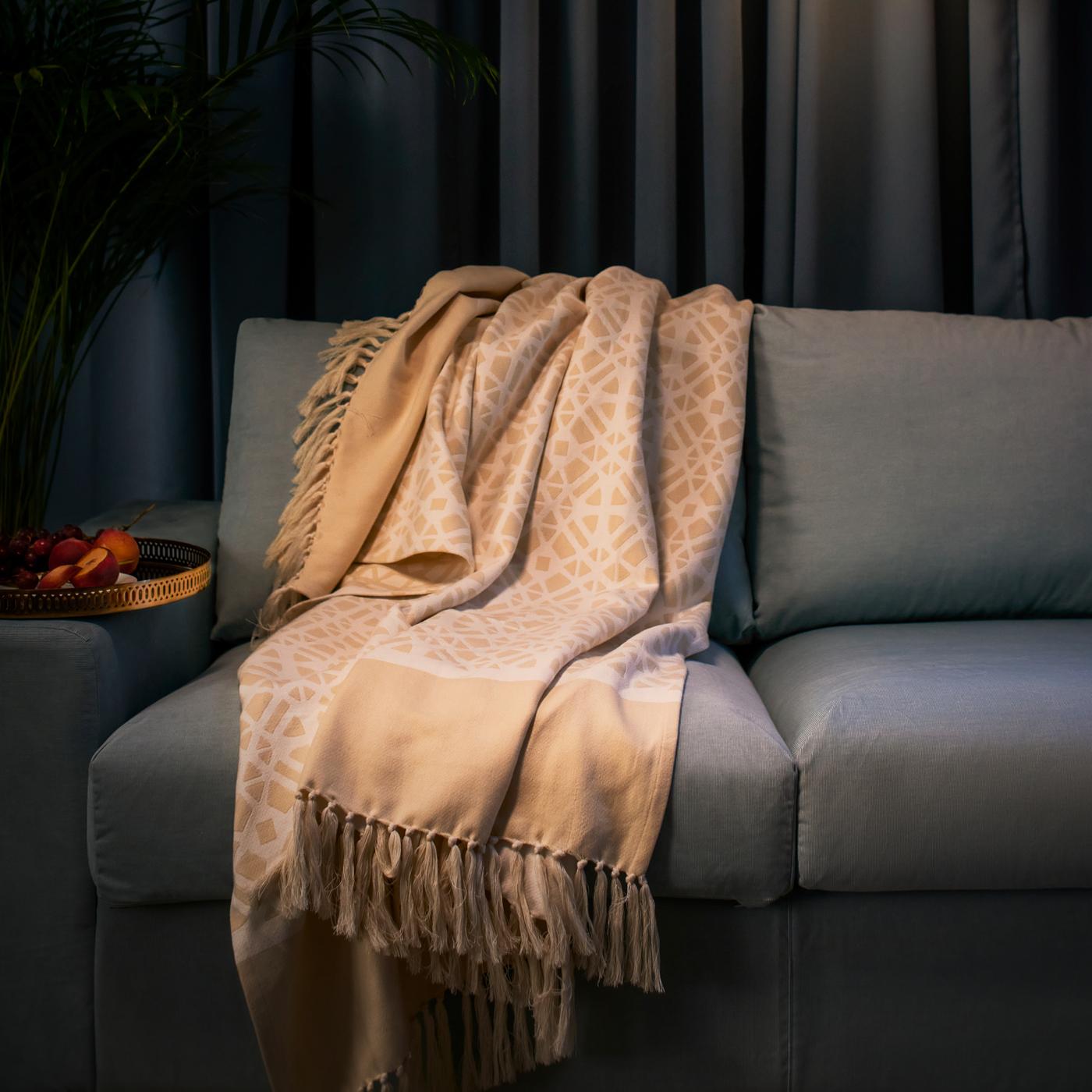 Una manta GOKVÄLLÅ sobre un sofá azul.