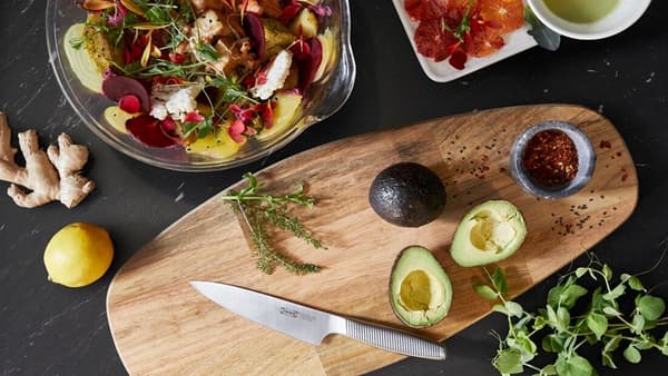 Una mesa con una tabla para picar FASCINERA donde se han cortado diversas verduras como paltas que serán parte de una ensalada.
