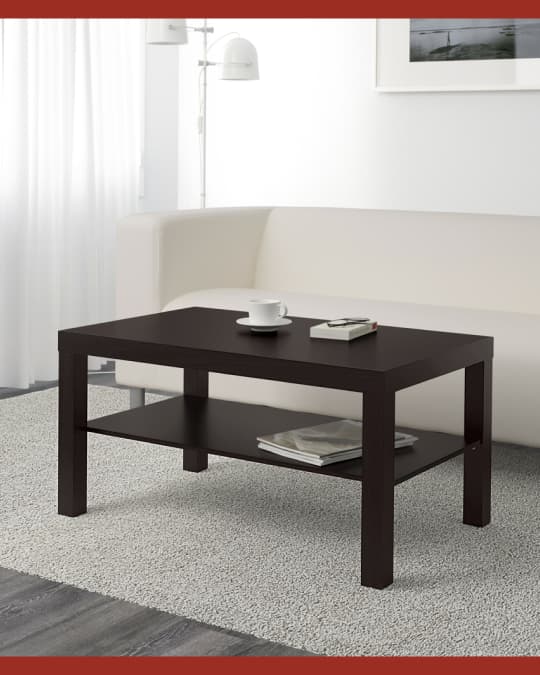 Una mesa de centro negra en una sala frente a un sofá blanco.