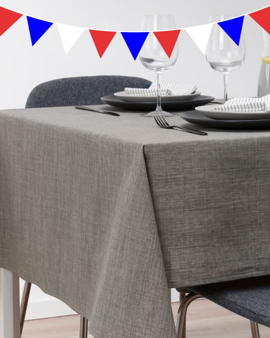 Una mesa de comedor rectanglar con un mantel gris de IKEA.