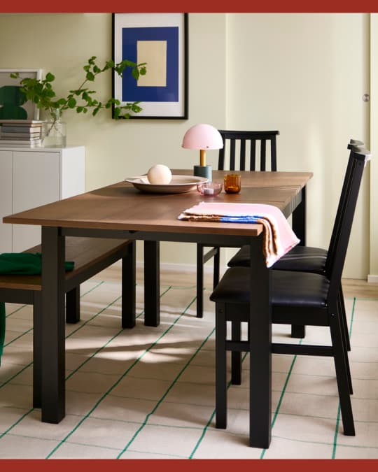 Una mesa de comedor rectángular con cubierta de madra y tres sillas y una banqueta.