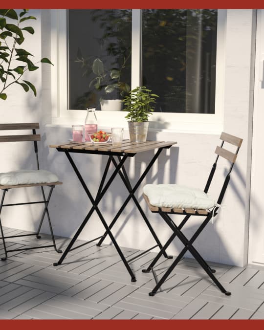 Una mesa de terraza plegable en un balcón con dos sillas plegables.