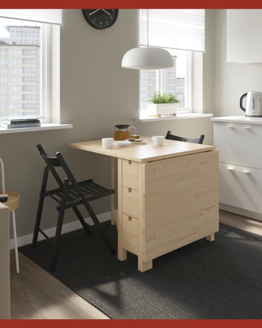 Una mesa NORDEN extendible con la mitad de la mesa extendida en una cocina y los tres cajones cerrados.