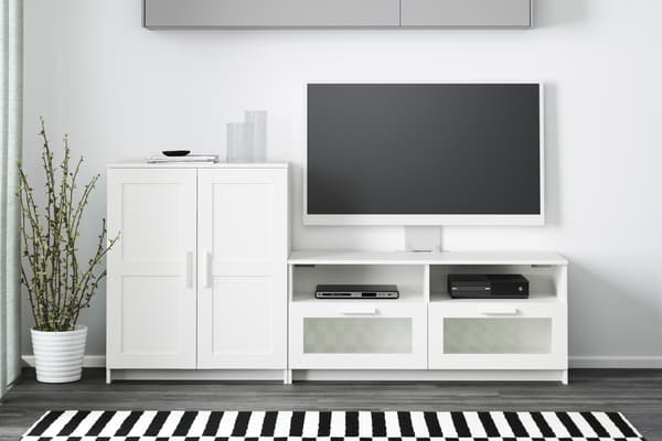 Una mesa para televisor blanca BRIMNES y al costado un gabinete blanco.