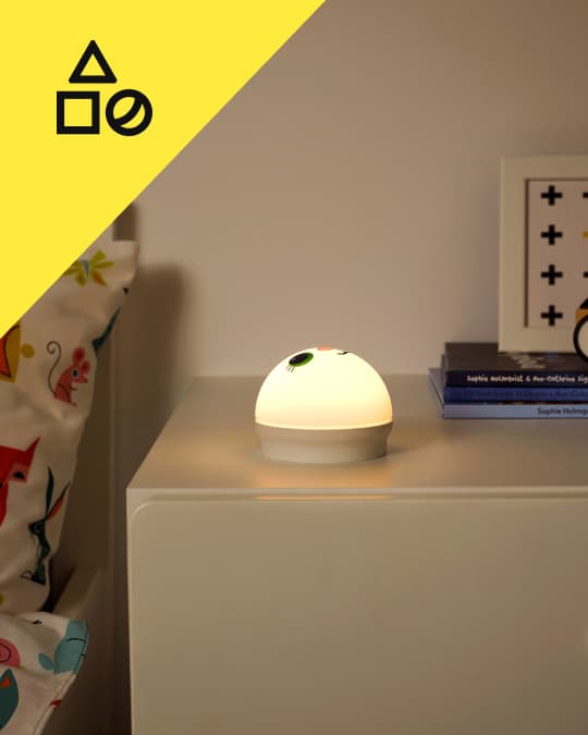 Una mesita de noche con una lámpara infantil encendida.