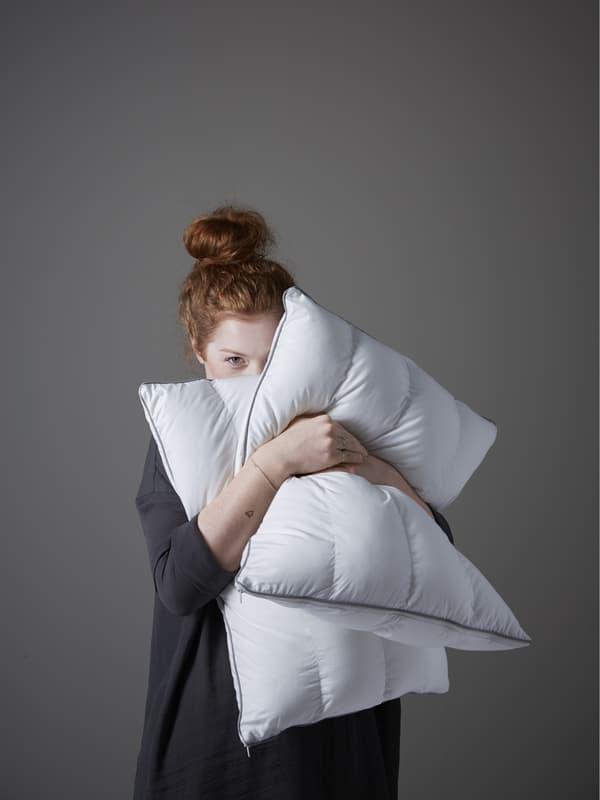 Una mujer sosteniendo almohadas en sus brazos.