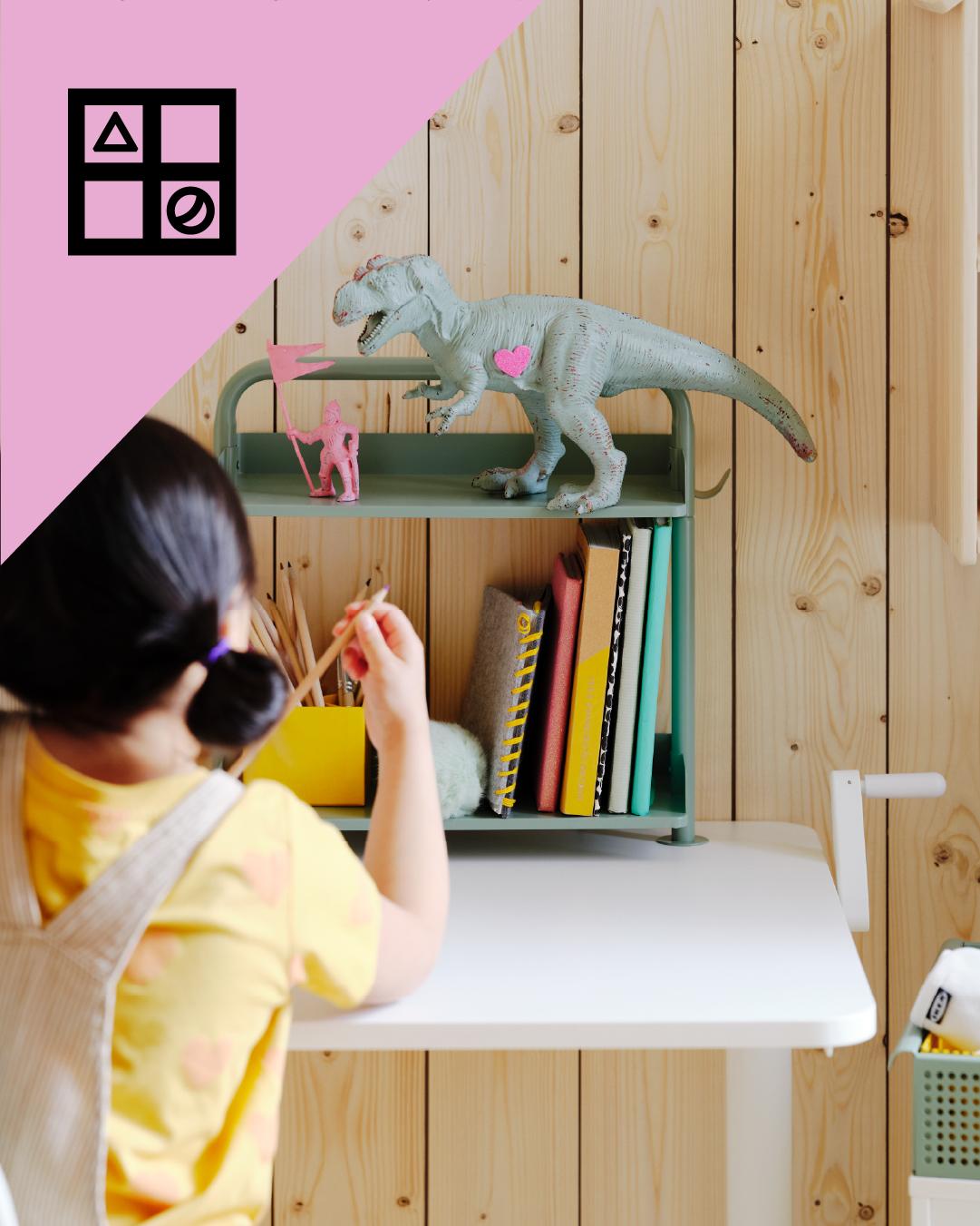 Una niña sacando un lápiz de una repisa organizadora de escritorio. En la esquina superior de la imagen un triángulo rosa con figuras geométricas.