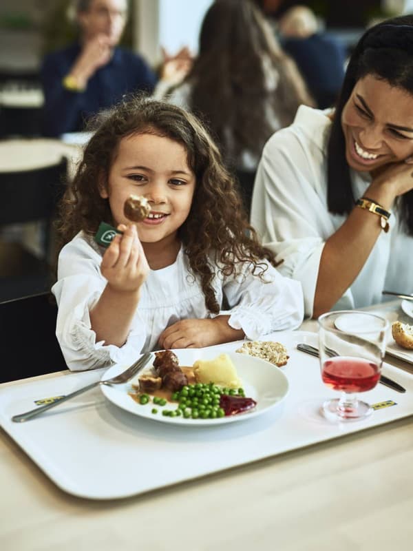 Una niña y una mujer adulta comiendo albóndigas en un Restaurante IKEA.