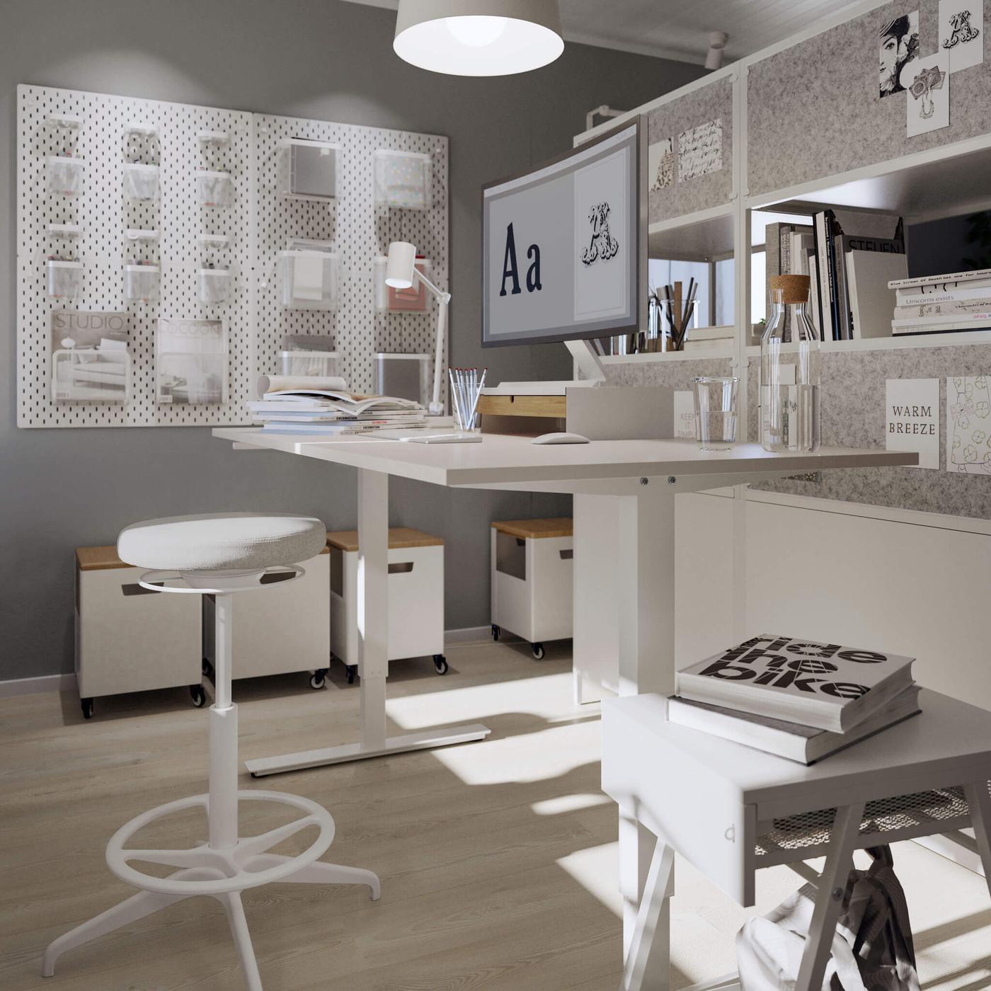 Una oficina con escritorio blanco y un asiento taburete, con almacenamiento blanco en las paredes.