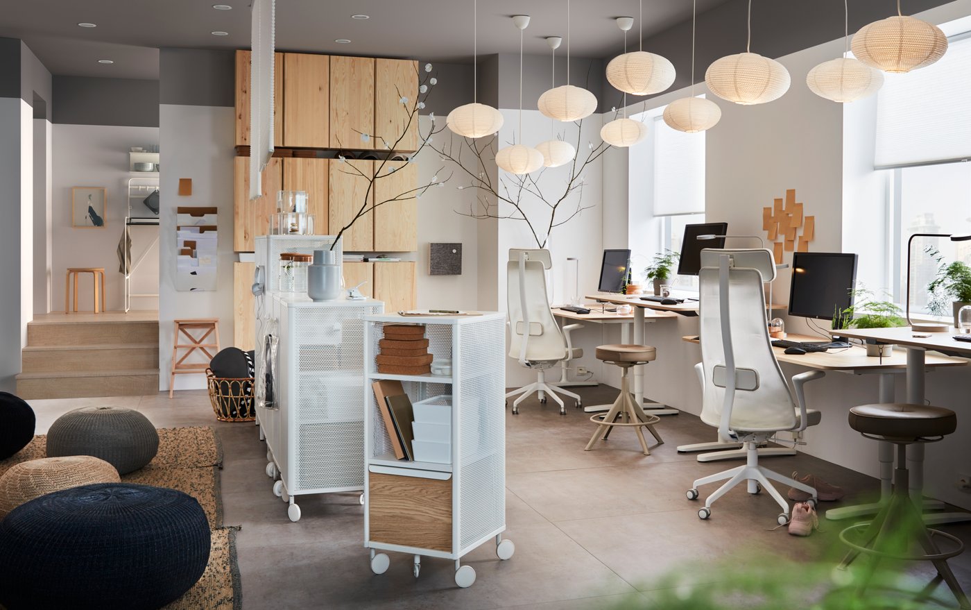 Una oficina con escritorios y cajoneras con ruedas.