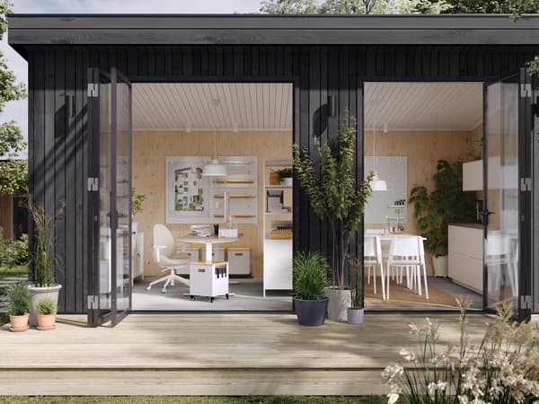 Una oficina de estilo moderno en un jardín con puertas de vidrio abiertas que muestran una zona de trabajo y una zona de comedor.