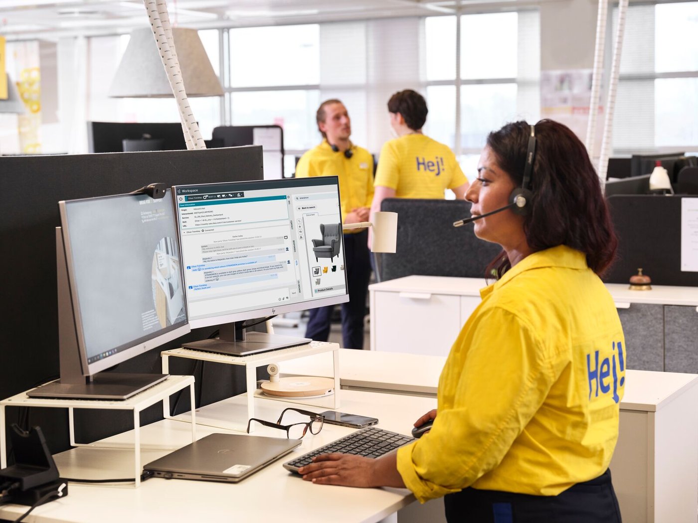 Una oficina d’IKEA amb tres empleats vestits de groc mirant les pantalles dels ordinadors.