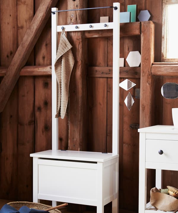 Una panca/contenitore HEMNES con pomelli e binario integrati utilizzabili come portasciugamani.