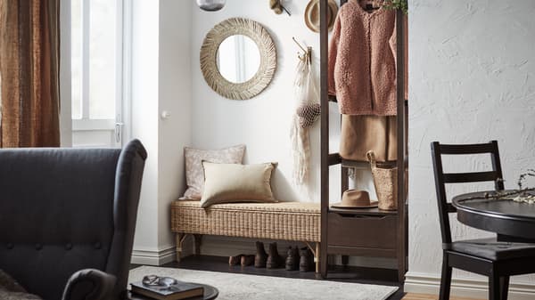 Una panca TOLKNING in rattan con contenitore in un ingresso con uno specchio VRIGSTAD sopra di essa e un guardaroba IDANÄS trattato con mordente marrone scuro accanto - IKEA.