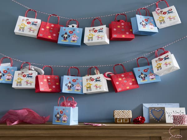 Una pared con dos tiras de bolsas de regalo colgando sobre una mesa de madera.