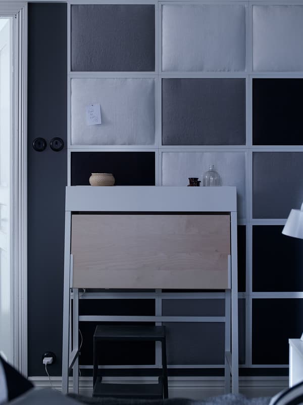 Una paret insonoritzant gris i blanca coberta amb marcs de fotos recoberts de teixit que redueix el soroll de l'interior de la casa.