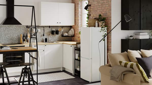 Una pequeña cocina diáfana equipada con módulos de la serie KNOXHULT. Hay una mesa HÅVERUD con escalera de almacenaje a un lado.