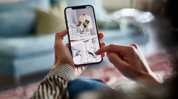 Una persona con in mano uno smartphone su cui è aperta l'app di IKEA.