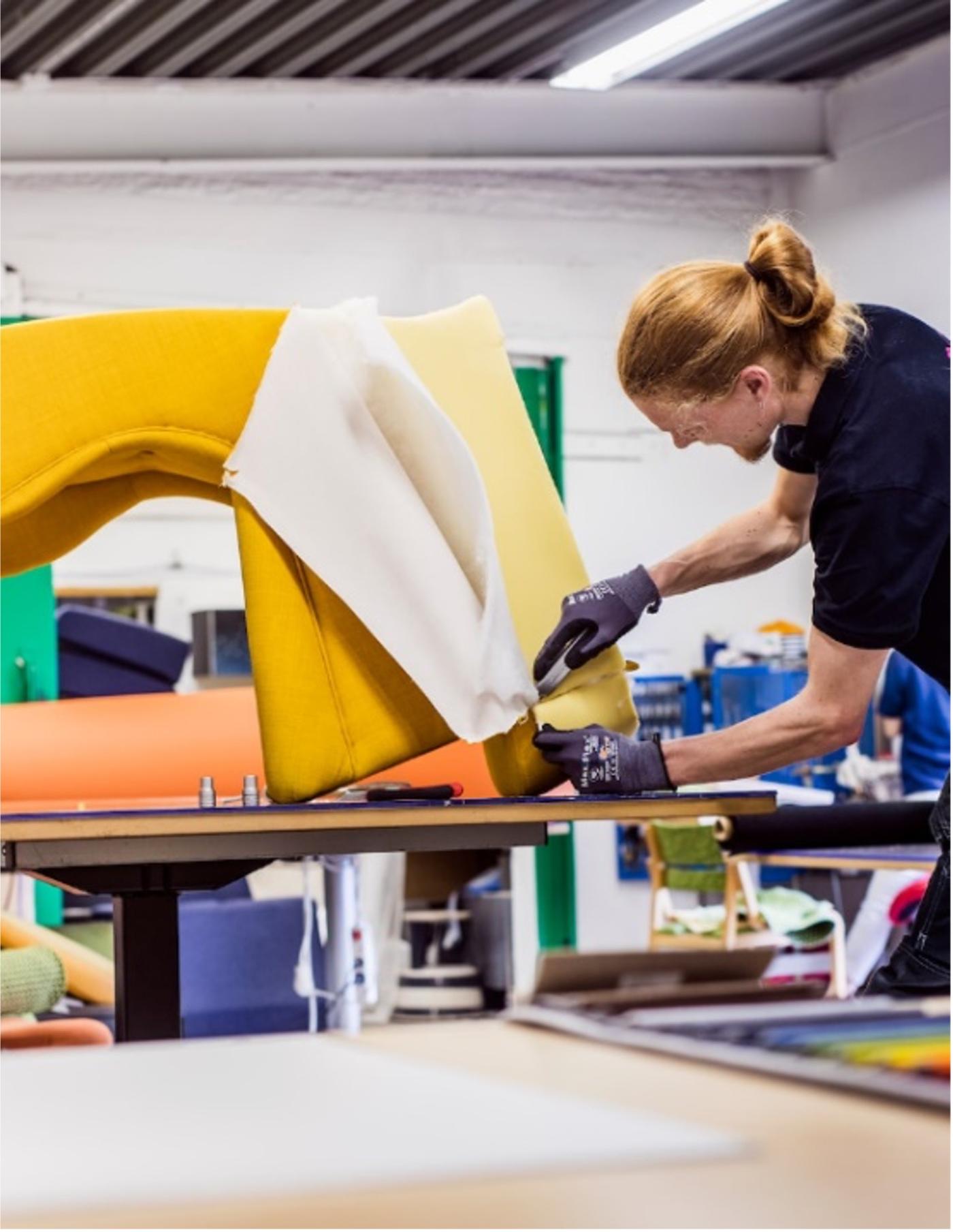 Una persona costruisce un divano giallo in un laboratorio.