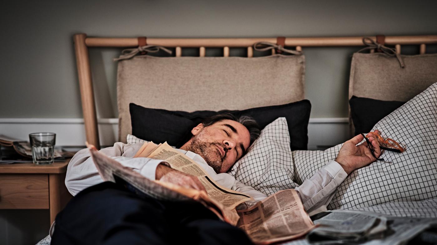 Una persona dorme in un letto BJÖRKSNÄS con copripiumino e 2 federe ÅKERFIBBLA.