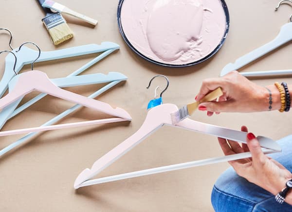 Una persona pintant un penja-robes BUMERANG de color rosa.