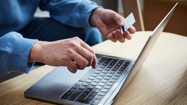 Una persona sentada en un escrtorio frete a un laptop.