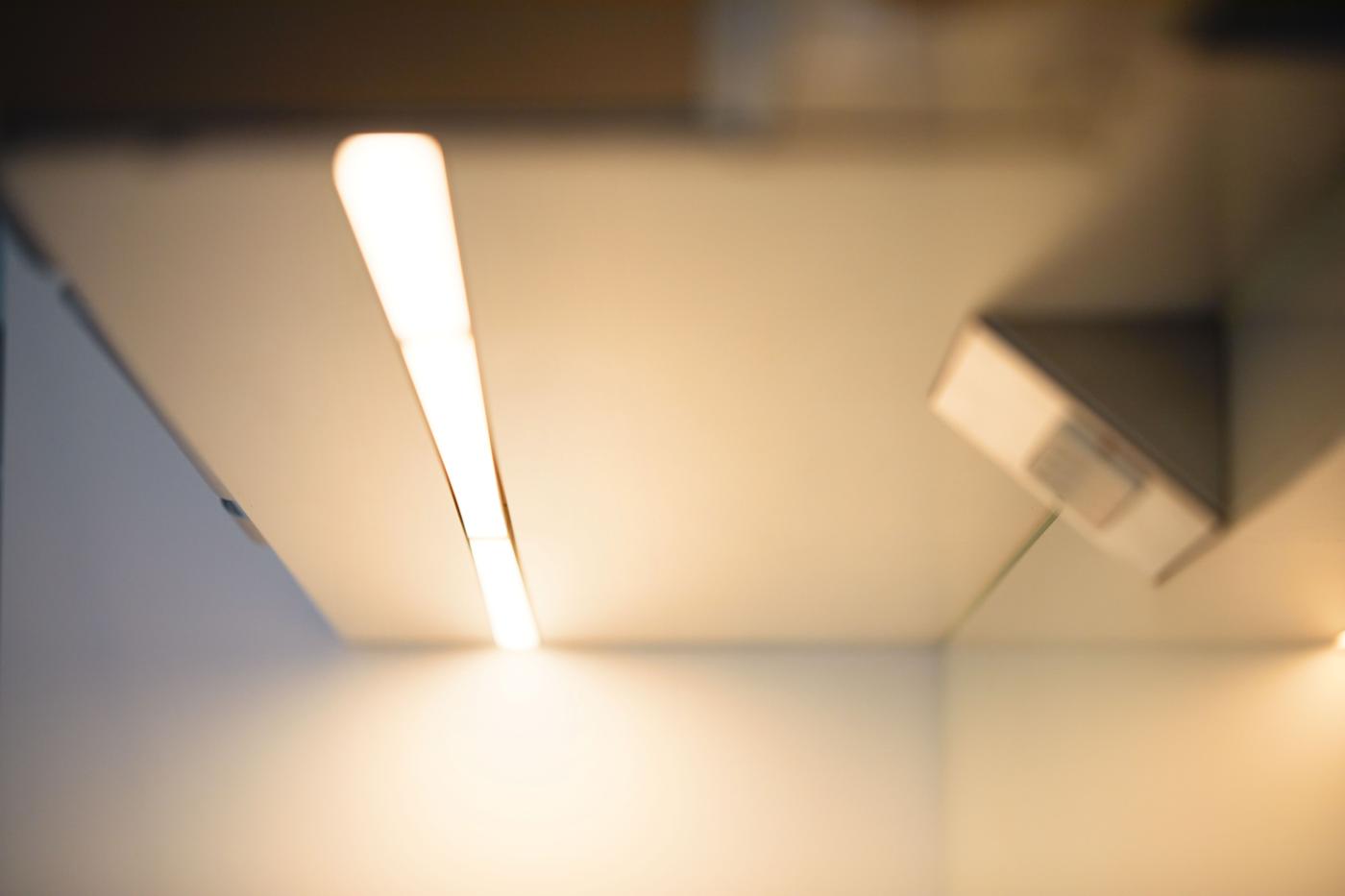 Una persona si trova in una cucina aziendale davanti a un distributore d'acqua e riempie un bicchiere con dell'acqua.