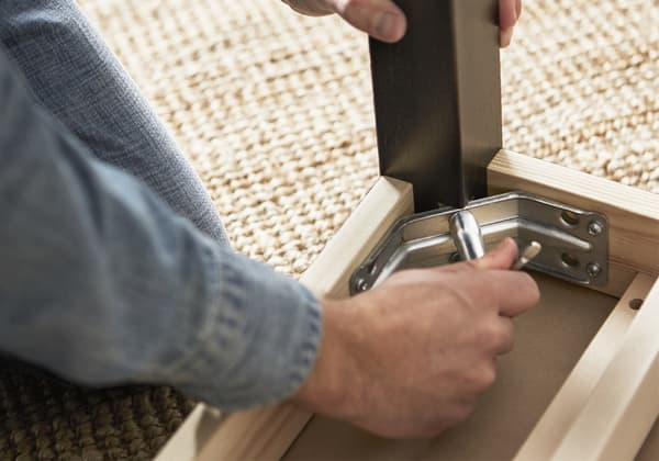 Una persona sta avvitando la gamba di un tavolo con la viteria IKEA.