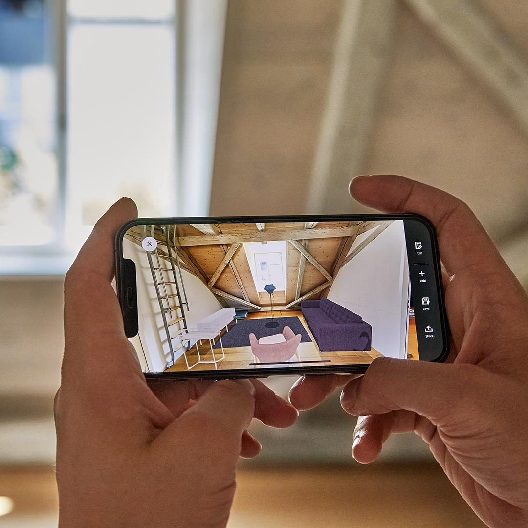 Una persona tiene lo smartphone di fronte a sé per progettare una stanza con l'IKEA Kreativ 3D Room Planner in Mixed Reality.