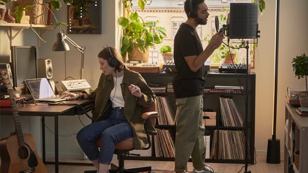 Una ragazza e un ragazzo che ascoltano musica con le cuffie in una stanza arredata come uno studio di registrazione musicale.