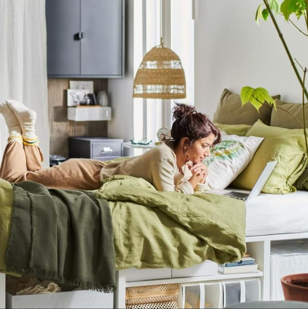 Una ragazza sdraiata mentre sta guardando un laptop. Sotto di lei, ci sono alcune scatole e contenitori.