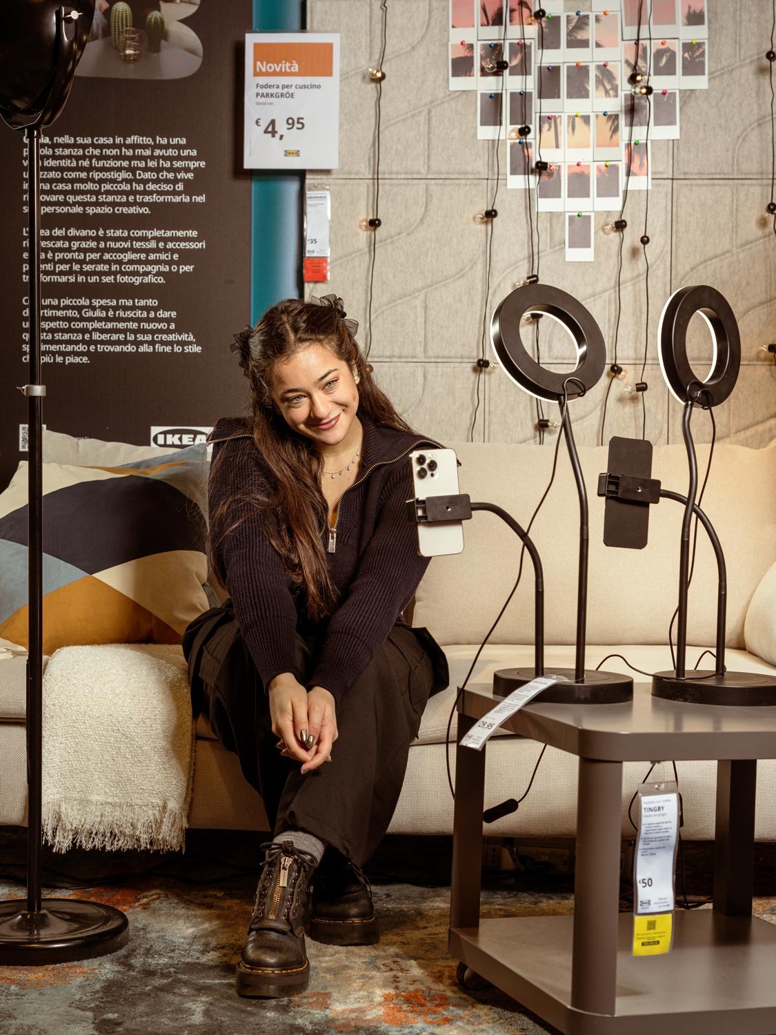 Una ragazza seduta su di un divano mentre sta registrando con uno smartphon collocato su un apposito supporto.