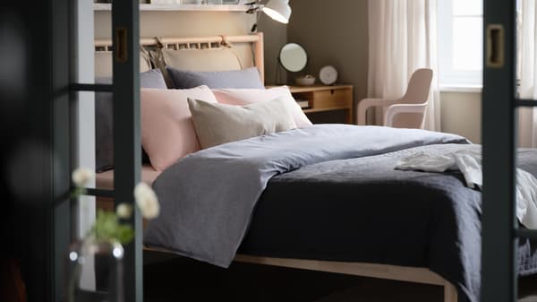 Una recámara con cama BJÖRKSNÄS, ropa de cama KOPPARBLAD azul oscuro, tocador NORDKISA y silla giratoria ODGER.