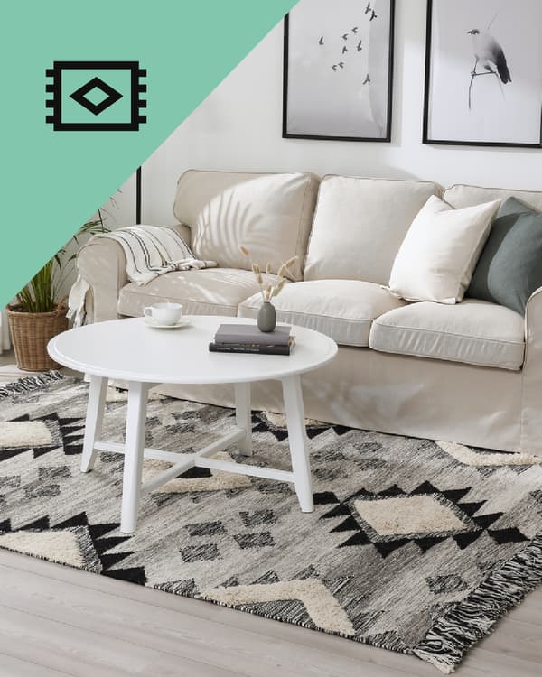 Una sala con un sofá blanco y frente a él un tapete hecho a mano de IKEA.