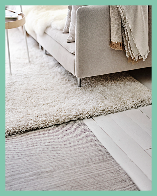 Una sala con un sofá cama sobre un tapete IKEA.