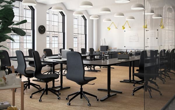 Una sala de juntes de planta oberta amb escriptoris de color marró-negre IKEA BEKANT i cadires giratòries ergonòmiques LÅNGFJÄLL en negre.