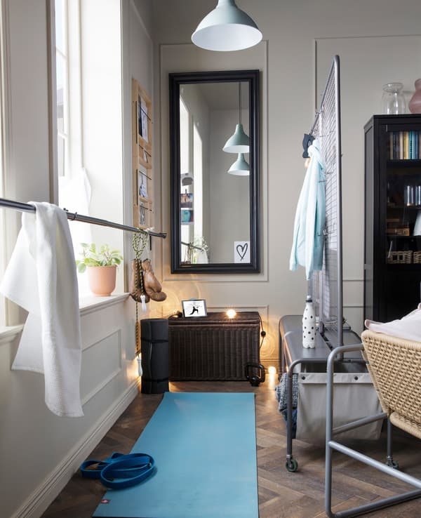 Una sala d'estar que està dividida amb un divisor IKEA VEBERÖD gris per crear una zona de ioga amb un mirall.