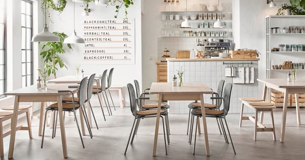 Una sala di un locale con sedie e tavoli della serie NORRÅKER disposte in maniera ordinata.