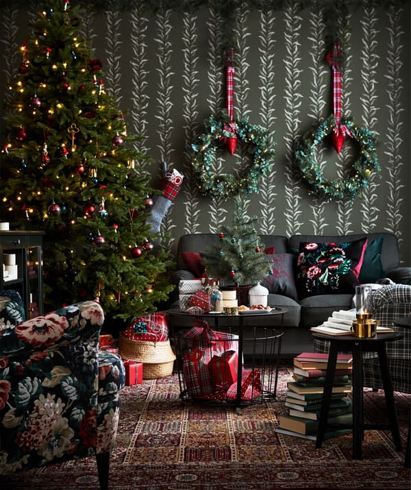 Una sala nadalenca decorada amb arbres i garlandes i una taula d'emmagatzematge GUALÖV davant d'un sofà.