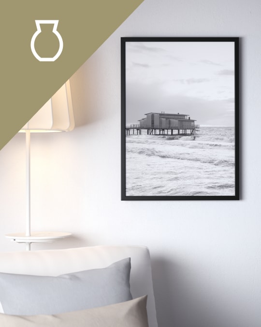 Una sala y al costado del sofá un cuadro con un marco de foto negro.