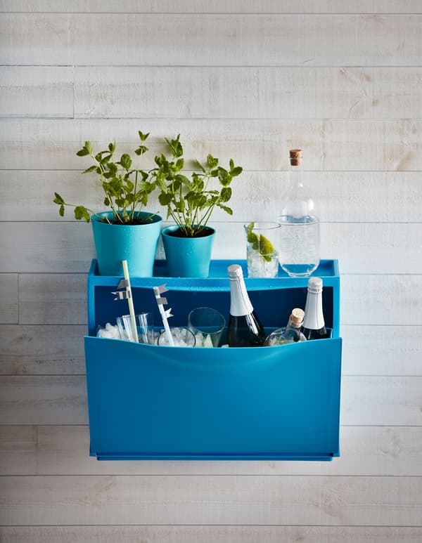 Una scarpiera TRONES blu usata come contenitore per ghiaccio, bicchieri e bottiglie di champagne, decorata con delle piantine - IKEA .