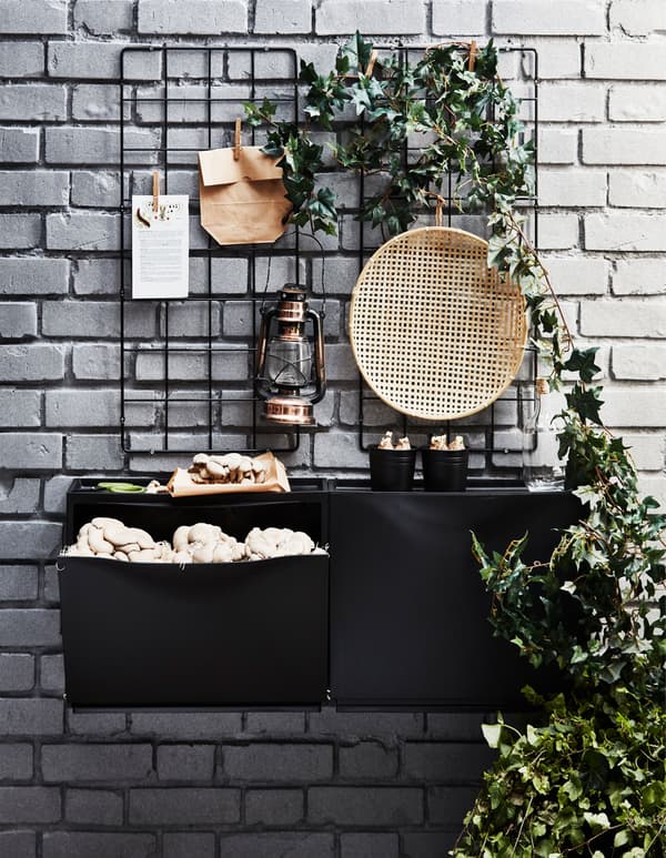 Una scarpiera TRONES nera appesa ad un muro di mattoni e usata come vaso per coltivare funghi all'aperto - IKEA.