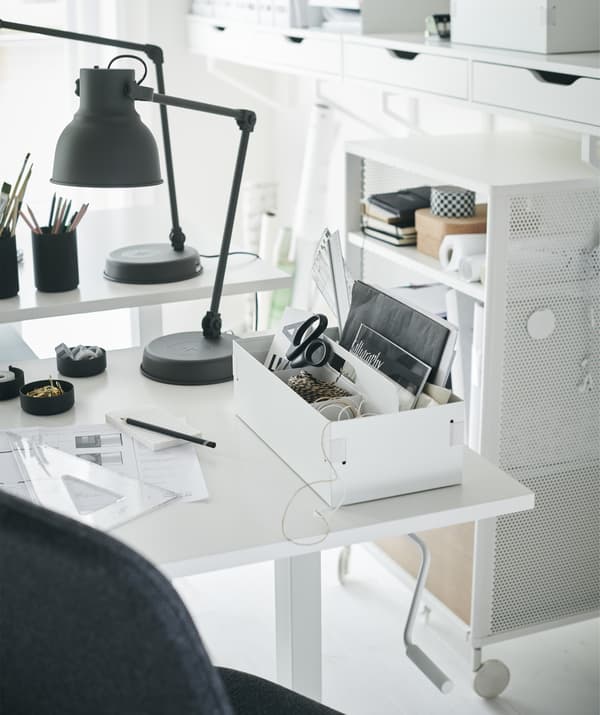 Una scrivania bianca ordinata e una lampada da lavoro grigio scuro - IKEA