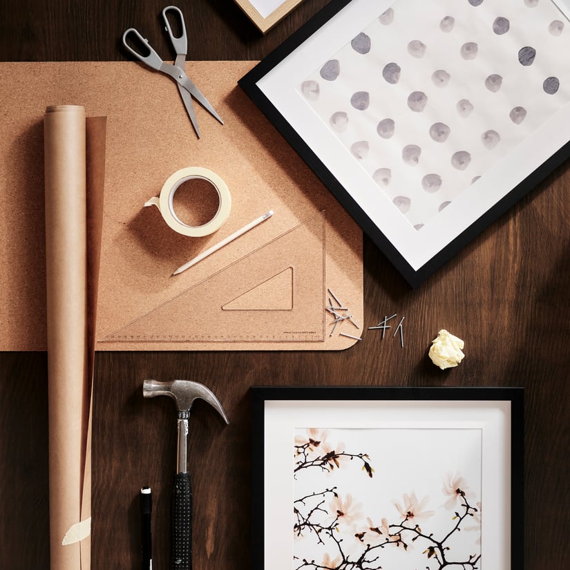 Una scrivania con alcune cornici e materiale per regolare e appendere le cornici alla parete.