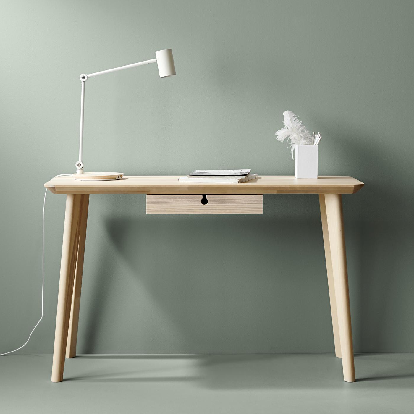 Una scrivania LISABO in legno con una lampada da tavolo e sullo sfondo una parete verde.